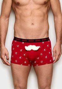 Rote Boxer-Briefs mit einem schwarzen Bund, der wiederholte Weihnachtsmann-Motive zeigt. Auffälliger weißer, flauschiger Schnurrbartakzent an der Vorderseite. Glatte Textur.