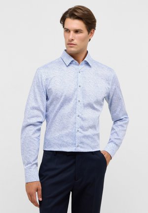 Lichtblauwe overhemd met lange mouwen, voorzien van een paisleypatroon, met knoopsluiting en knopen aan de voorkant, gecombineerd met donkergekleurde broek.