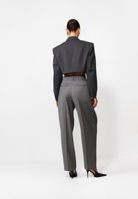 Szary skrojony żakiet z poduszkami na ramionach oraz dopasowane szare wzorzyste spodnie. Uzupełnione eleganckimi czarnymi szpilkami, tworzą nowoczesną sylwetkę.