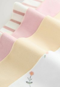 Set van stoffenstalen met zachte texturen in pastelkleuren: roze, geel en wit met bloemenpatronen en strepen.
