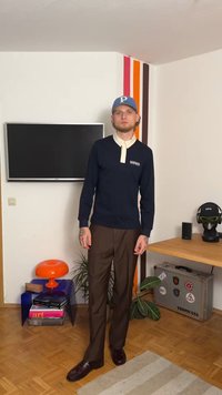 Camiseta de manga larga azul marino con cuello blanco y logotipo, combinada con pantalones de pierna recta marrones y zapatos oscuros. Presenta un diseño minimalista.