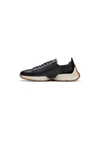 Zapato deportivo negro con parte superior de cuero, detalles perforados, cordones grises, entresuela acolchada beige y suela de goma con agarre texturizado.