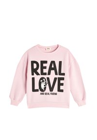 Rosa bomullströja med rundad hals, sänkta axlar, fet svart text som säger "VERKLIG KÄRLEK" och en grafik av en hund, ribbade manschetter och nederkant.