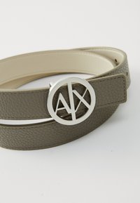Cinto de couro cinza com uma textura suave, apresentando uma fivela redonda prateada em destaque, gravada com o logótipo "AX".