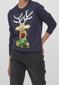 Pull en maille bleu marine avec un motif de renne en sequins dorés et verts. Col rond classique et poignets côtelés.