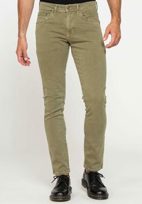 Chinos ajustés vert olive avec cinq poches et une fermeture éclair, fabriqués en coton doux et durable. Présente un design simple.