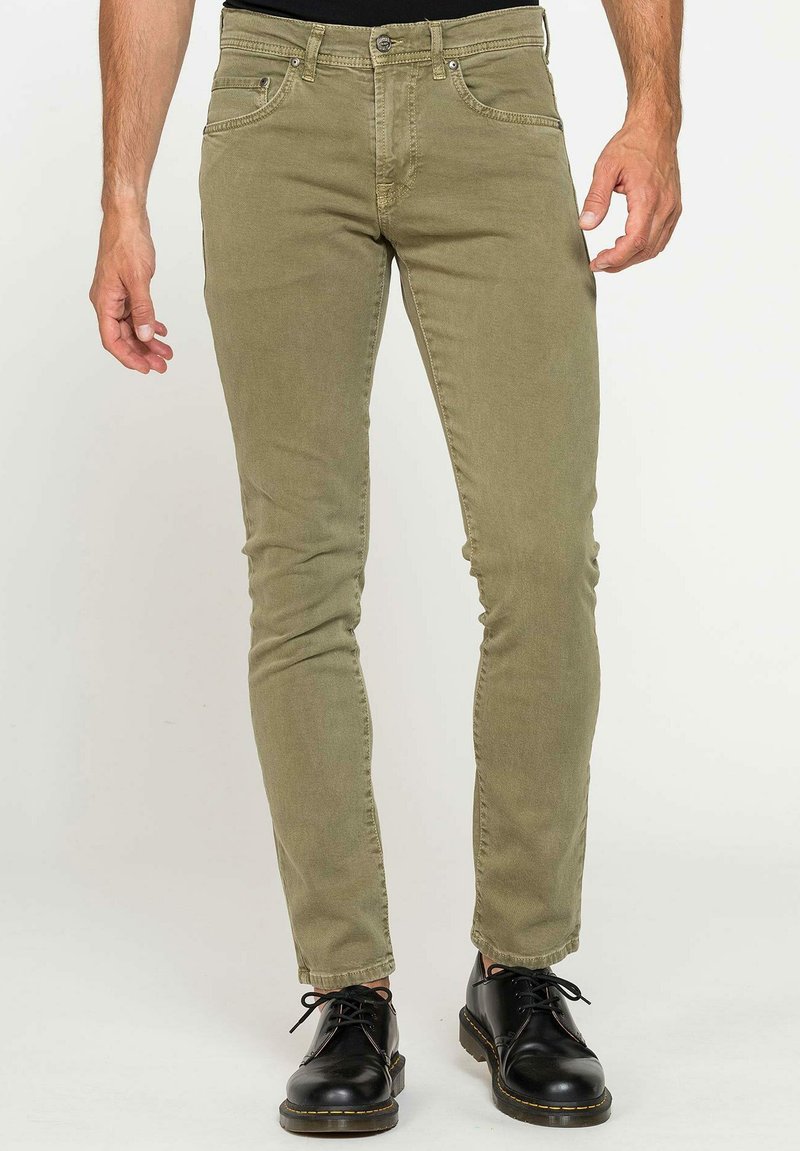 Chinos ajustés vert olive avec cinq poches et une fermeture éclair, fabriqués en coton doux et durable. Présente un design simple.