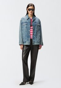 Jean jakna s dva džepa na prsima, svijetloplava nijansa, dugmad zatvaranje. Uparena s crnim kožnim hlačama i ružičasto-crnom prugastom duksericom.
