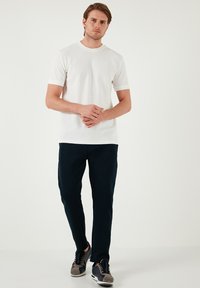 Witte korte mouw crewneck t-shirt gecombineerd met marineblauwe tapered pants en grijze sneakers, met een gladde textuur en een strakke uitstraling.