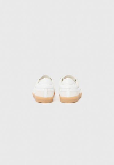 Baskets en cuir blanc avec une silhouette basse, un dos rond et des semelles en caoutchouc beige. Présentent des coutures minimalistes et une texture lisse.