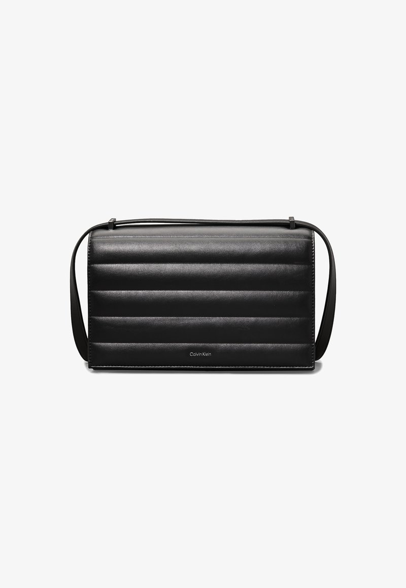 Svart läderväska med en quiltad design, lång justerbar axelrem och en diskret Calvin Klein-logotyp längst ner. Rektangulär form med slät yta.