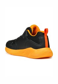Sneaker nera con accenti arancioni, caratterizzata da una tomaia in mesh testurizzato, cinturino a strappo e una suola in gomma arancione ammortizzata.