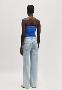 Lichtblauwe high-waisted wijde jeans in combinatie met een nauwsluitende blauwe strapless top. Kenmerken zijn onder andere vier zakken en een ontspannen silhouet.