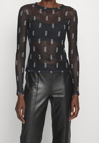 Schwarzes Mesh-Longsleeve-Oberteil mit einem wiederholten Logo-Muster. Enganliegendes Design mit Rundhalsausschnitt und gerippten Bündchen.