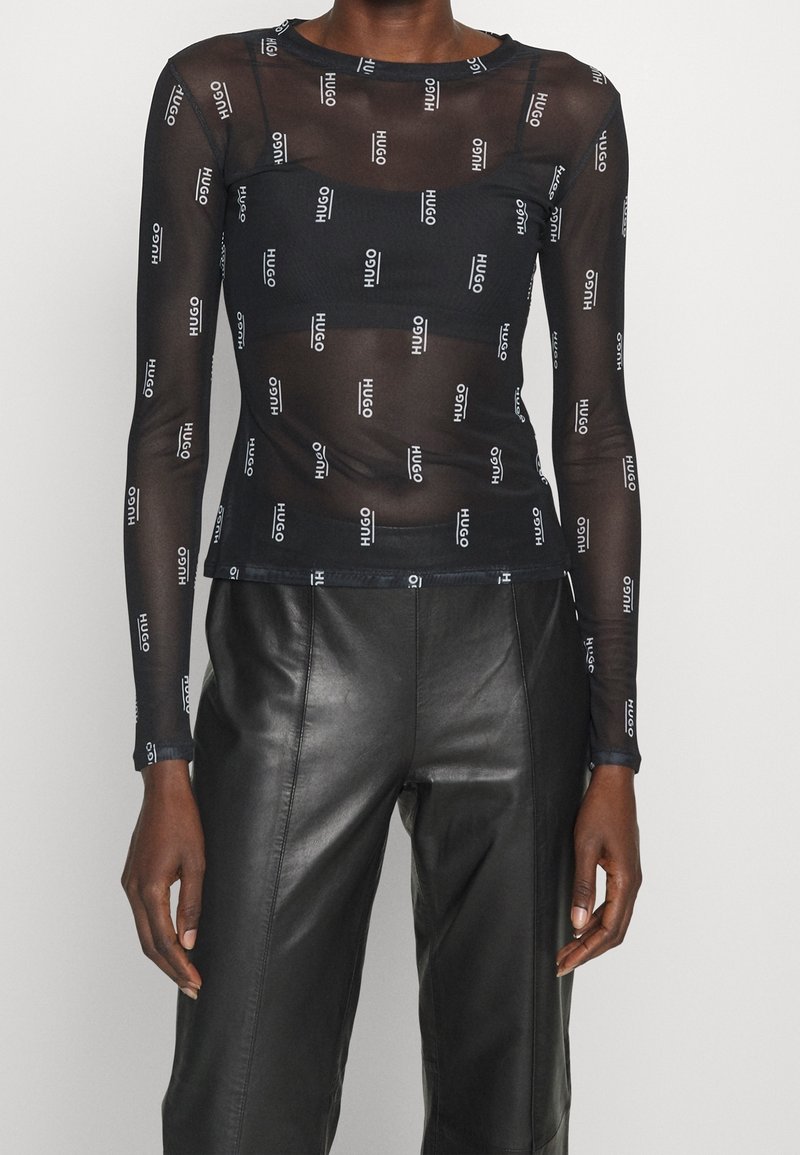 Schwarzes Mesh-Longsleeve-Oberteil mit einem wiederholten Logo-Muster. Enganliegendes Design mit Rundhalsausschnitt und gerippten Bündchen.
