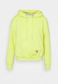 Jasnozielona bluza z kapturem z przednią kieszenią typu kangur i powtarzającym się logo "cK" w kolorze czarnym na dolnej części kieszeni.