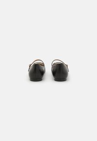 Bailarinas de cuero negro con punta redondeada y correa en el tobillo, que presentan una textura suave y un diseño minimalista.