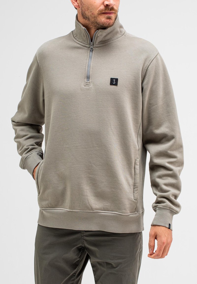 Grau Fleece-Pullover mit halbem Reißverschlusskragen, Seitentaschen, gerippten Bündchen und einem kleinen schwarzen Logopatch auf der Brust. Glatte Textur, lässiges Design.