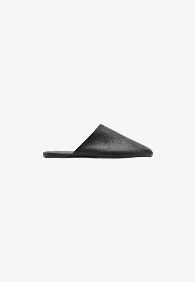 Mules negros de cuero con diseño de punta, suela plana y textura suave. Estilo minimalista sin herrajes ni adornos.
