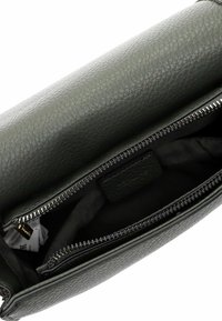 Sac en cuir vert foncé avec une surface texturée, doté d'une fermeture éclair et d'un intérieur en tissu noir. L'intérieur comprend des compartiments.