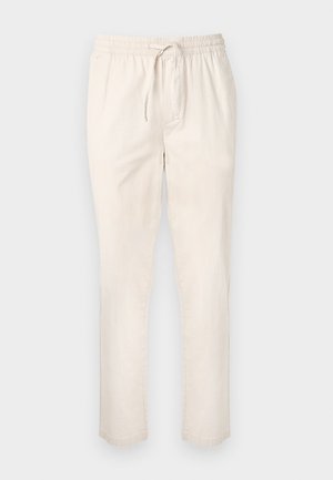 Pantalon beige clair avec taille élastique et cordon de serrage. Coupe droite, texture douce, coutures minimales, sans poches visibles.