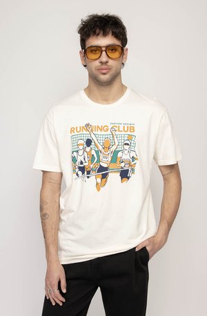 Cream-colored cotton t-shirt featuring a colorful graphic of runners, with "RUNNING CLUB" text and distinct outlines. Worn with dark pants.