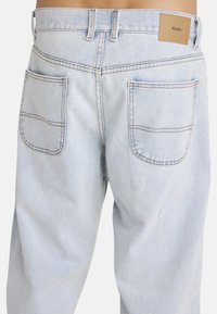 Lichtblauwe denim jeans met een relaxte pasvorm, voorzien van twee achterzakken en contrasterende stiksels. Het merkembleem is van bruin leer en bevindt zich op de tailleband.
