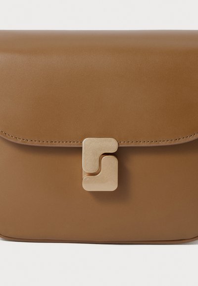 Borsa in pelle marrone con una patta liscia e una chiusura geometrica dorata centrata sul fronte, con bordi cuciti visibili sulla patta.