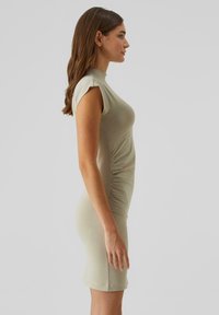 Testhez simuló, rövid ujjú, zsályazöld ruha sima anyagból, oldalán ráncolt és magas nyakkivágással, térd alatti hosszúsággal.