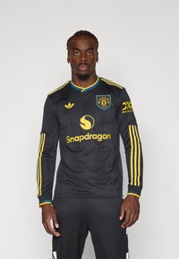Black long-sleeve soccer jersey featuring yellow stripes, a round collar, and a logo with "Snapdragon" printed on the front.