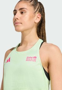 Svijetlozeleni atletski top s ružičastim printom koji prikazuje "BMW BERLIN MARATHON." Dizajniran s racerback krojem i teksturiranom tkaninom.