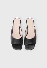 Μαύρα δερμάτινα σανδάλια με φαρδιά λωρίδα που καλύπτει το πέλμα, τετράγωνη μύτη και λείο ματ φινίρισμα. Φωτεινή φόδρα με χρυσό λογότυπο.