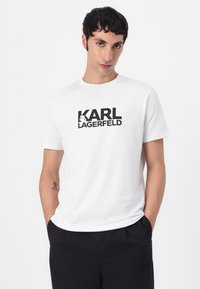 Hvit bomull T-skjorte med en dristig svart "KARL LAGERFELD" logo over brystet. Korte ermer og design med rund hals.