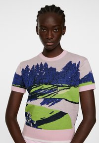 Sweter dziany z krótkim rękawem z różowym wykończeniem oraz malowniczym wzorem w kolorach zielonym, niebieskim i czarnym przedstawiającym krajobraz pola golfowego.