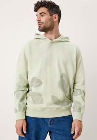 Felpa verde chiaro con un motivo di foglie a trama in una tonalità più scura. Presenta una tasca a marsupio frontale e polsini a costine, realizzata in materiale morbido.