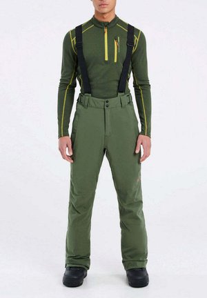 Pantalons de ski verts avec bretelles noires réglables, deux boutons à l'avant et poches latérales. Porté sur un haut ajusté à manches longues avec des accents jaunes.