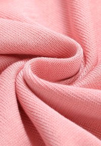 Tissu tricoté rose doux avec des coutures fines, plié en douceur pour montrer la texture et les détails du tissage.