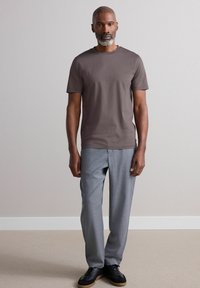 Camiseta gris de manga corta combinada con pantalones gris claro y zapatillas negras. El conjunto presenta un diseño simple y moderno sin patrones.