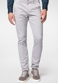 Světlé šedé chinos s úzkým střihem, s hladkým povrchem, standardními kapsami a zapínáním na knoflík, doplněné šedými teniskami.