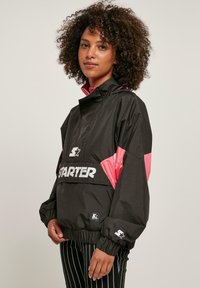 Zwarte en roze lichtgewicht anorakjas met elastische manchetten, een hoge kraag en logo-details aan de voorkant. Heeft een ontworpen kleurgeblokt patroon.