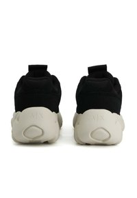 Sneaker nere con suole bianche spesse viste da dietro, con il marchio A|X impresso nella zona del tallone.