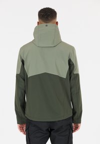 Veste pour homme en blocs de couleurs vert foncé et vert clair. Présente un col élevé, une capuche ajustable et un tissu lisse et résistant à l'eau.