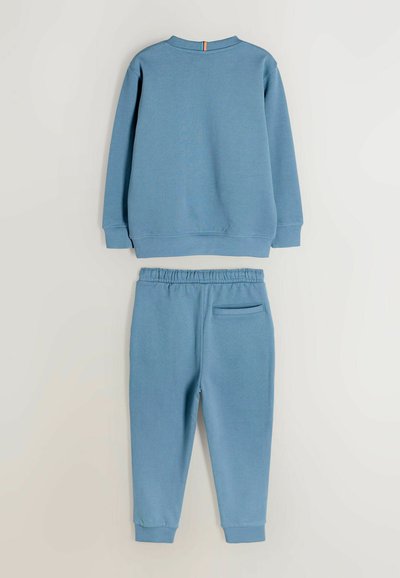 Niebieski bawełniany sweatshirt oraz dopasowane spodnie, z długimi rękawami, ściągaczami oraz tylną kieszenią w talii. Prosty design z minimalnymi akcentami.