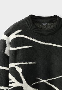 Jersey negro de punto con patrones abstractos en blanco que se asemejan a ramas y un cuello redondo acanalado.