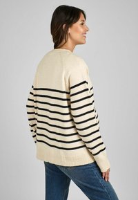 Maglione crema con strisce orizzontali nere, polsini e orlo a coste, vestibilità rilassata. Texture morbida, cuciture visibili, senza chiusure.