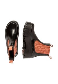 Botas Chelsea negras con un patrón geométrico texturizado en naranja en el costado. Presenta una suela gruesa con surcos profundos y tiradores para facilitar su uso.