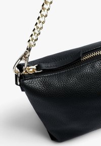 Sort læder clutch taske med en tekstureret overflade, guld kædestrop og lynlås. Har en detalje i guld metal ved stropperne.