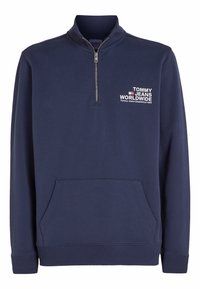 Felpa con zip di colore blu navy, colletto alto, tasca frontale, polsini a coste e logo "TOMMY JEANS WORLDWIDE" sul lato sinistro del petto.