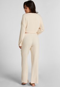 Beige loungekleding set van twee delen met een kortere lange mouw top en wijde broekspijpen, gemaakt van zachte stof met een relaxte pasvorm.
