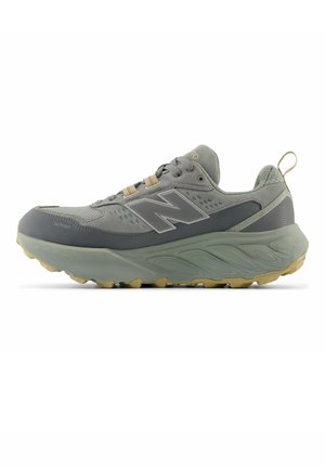Grijze en beige New Balance sportschoen met dikke zool, vetersluiting aan de voorkant, trek lusje bij de hiel en logo aan de zijkant.